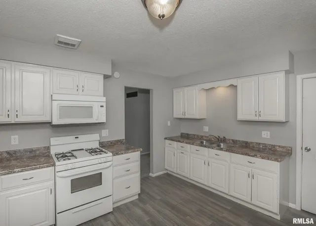 a kitchen with granite countertop white cabinets and white appliances