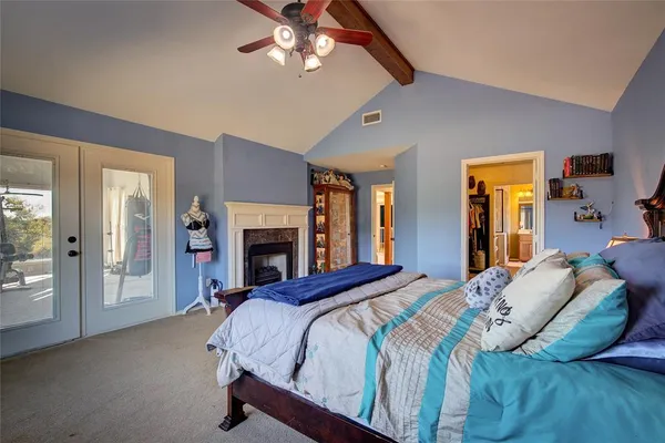 a bed sitting in a spacious bedroom next to a window and a chandelier