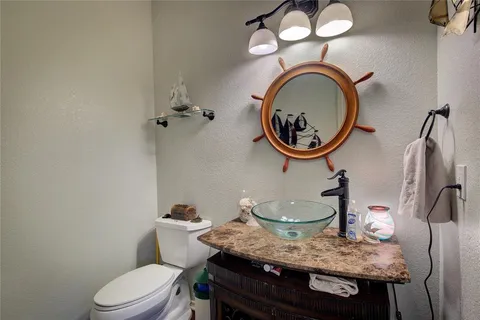 a bathroom with a granite countertop toilet a sink and a mirror