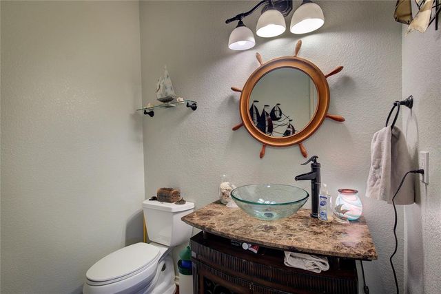 a bathroom with a granite countertop toilet a sink and a mirror