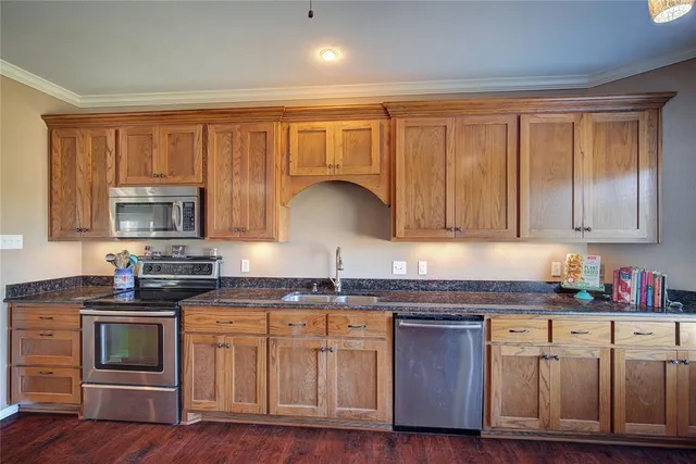 a kitchen with stainless steel appliances granite countertop a stove a sink dishwasher and a microwave oven with wooden floor