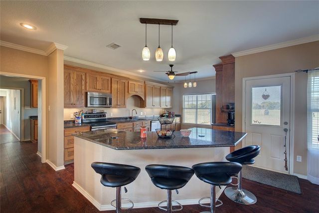 a kitchen with stainless steel appliances granite countertop a kitchen island and chairs in it