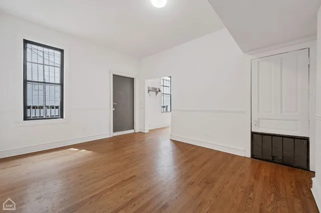 an empty room with wooden floor a fireplace and windows