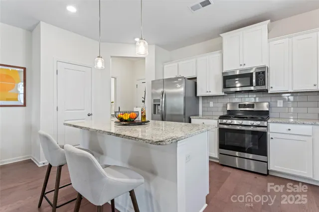 a kitchen with stainless steel appliances granite countertop a sink a stove a microwave and cabinets