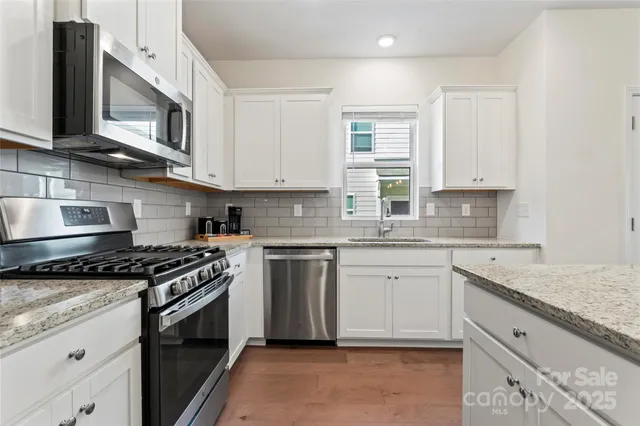 a kitchen with stainless steel appliances granite countertop a sink refrigerator and cabinets