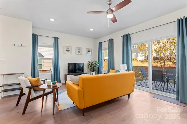 a living room with furniture kitchen view and a wooden floor