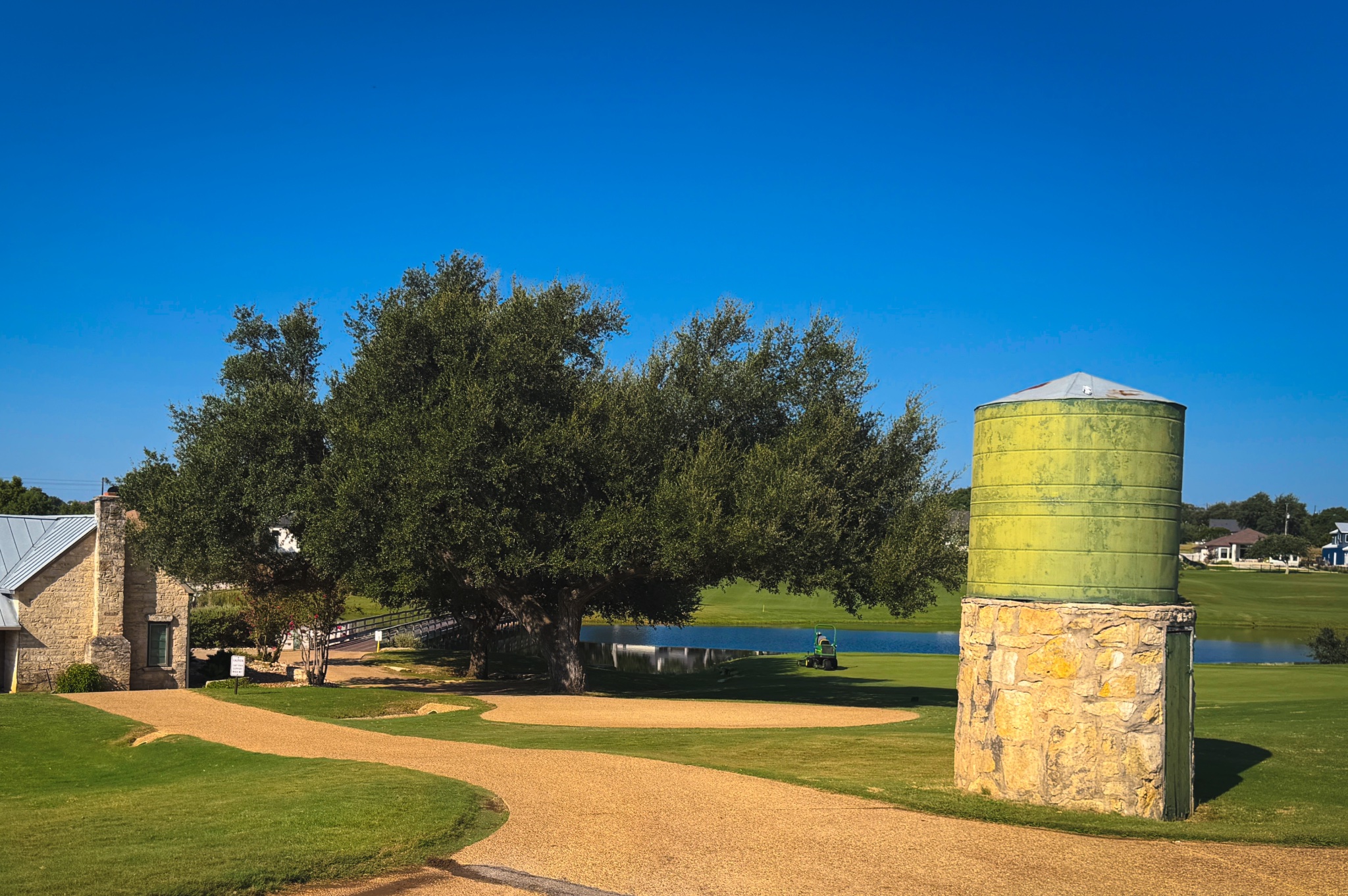 Lot 380 South Calvin Barrett Road Blanco, TX 78606 - Photo 14 of 24 A picturesque rural setting featuring a winding gravel path, mature trees, and a tranquil body of water.