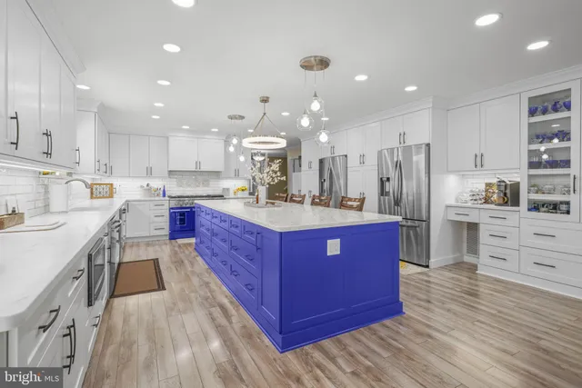 a kitchen with stainless steel appliances kitchen island granite countertop a table chairs sink and cabinets