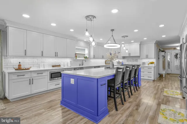 a kitchen with a sink dishwasher a stove and white cabinets with wooden floor