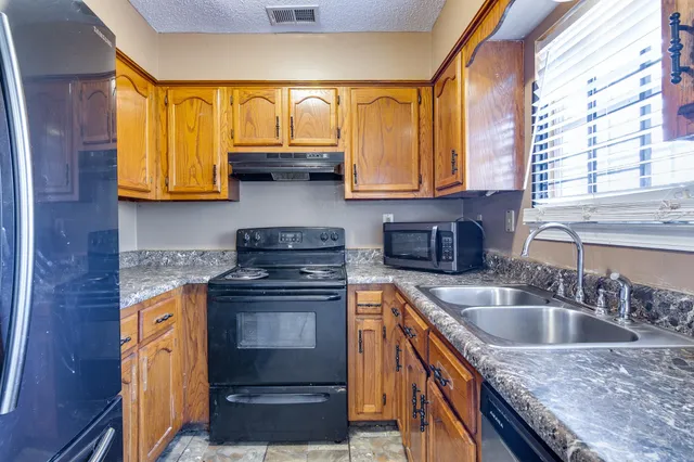 a kitchen with granite countertop a sink a counter top space and cabinets