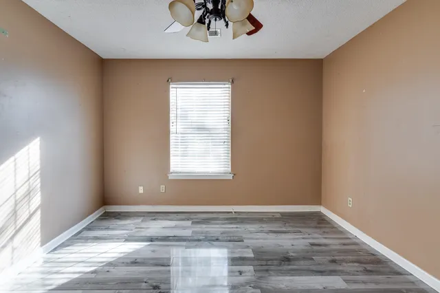a view of an empty room with wooden floor and a window