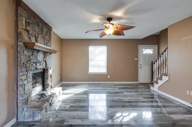 a view of an empty room with wooden floor and a fireplace