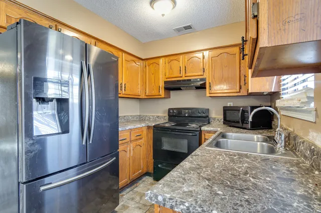 a kitchen with stainless steel appliances granite countertop a refrigerator a stove a sink and a microwave