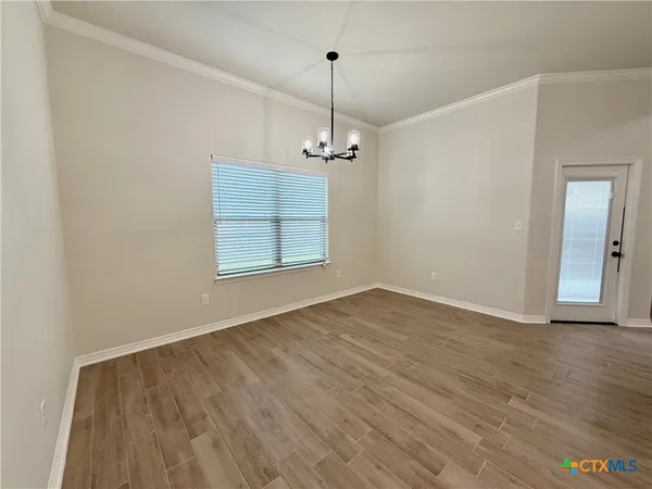 an empty room with wooden floor windows and cabinet