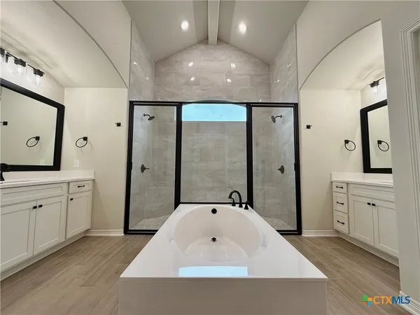 a spacious bathroom with a tub sink and mirror
