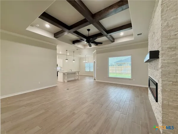 a view of an empty room with wooden floor and a fireplace