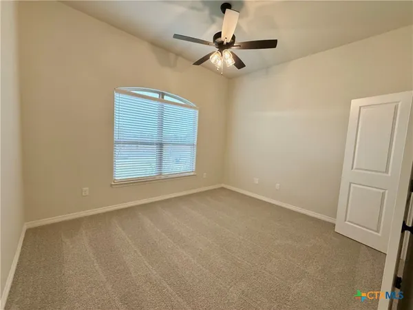 an empty room with windows and fan