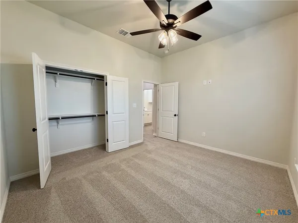 an empty room with closet and a ceiling fan