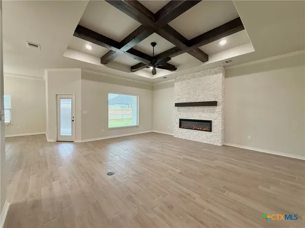 an empty room with wooden floor a ceiling fan and windows