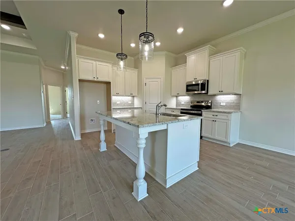 a kitchen with kitchen island granite countertop a sink a counter top space stainless steel appliances and cabinets