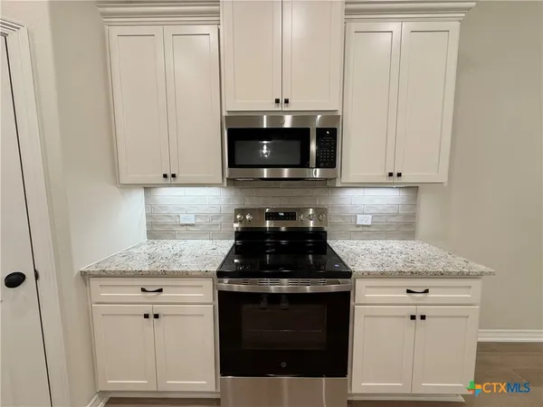 a kitchen with granite countertop white cabinets and stainless steel appliances