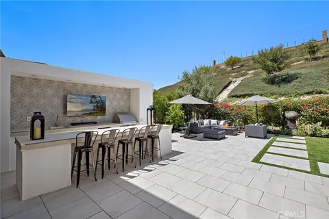 a view of a patio with dining table and chairs with a barbeque grill and plants