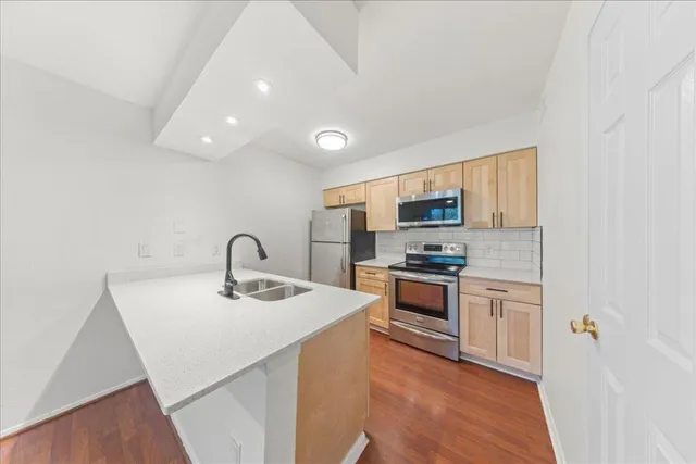 a kitchen with stainless steel appliances granite countertop a sink stove microwave and refrigerator