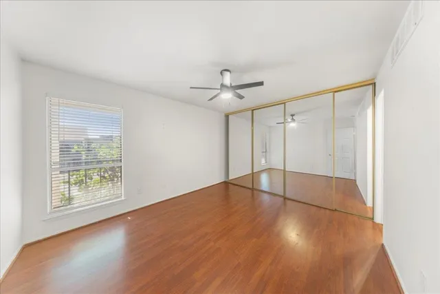 a large white kitchen with wooden floor and a ceiling fan