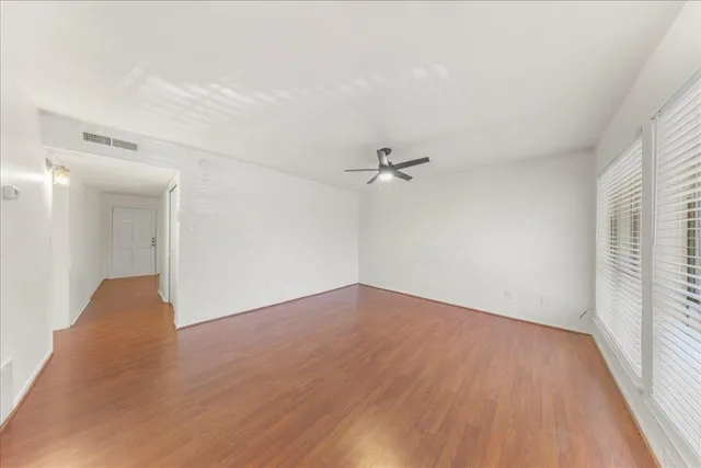 an empty room with wooden floor and windows