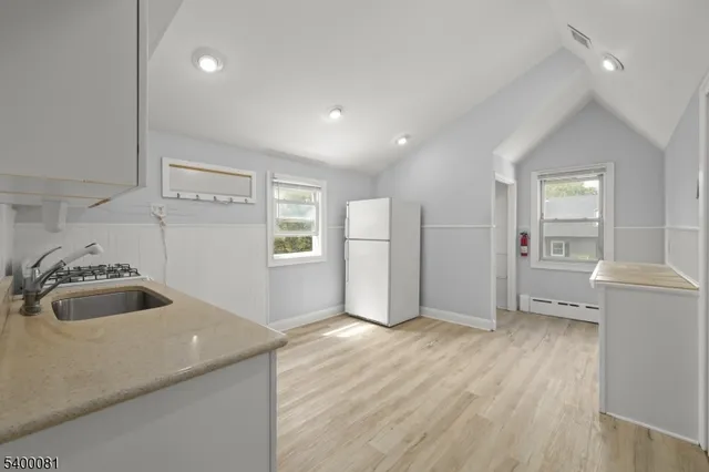 a view of a kitchen with a sink and dishwasher a refrigerator with white cabinets