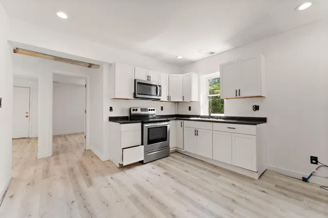 a kitchen with granite countertop a stove a sink and a microwave