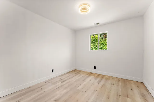 an empty room with wooden floor and window