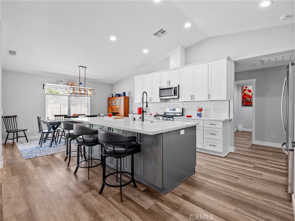 24162 Shoshone Road Apple Valley, CA 92307 - Photo 6 of 40 a kitchen with stainless steel appliances kitchen island granite countertop a table chairs sink and cabinets