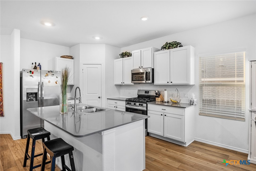 1909 Four Waters Loop Georgetown, TX 78628 - Photo 8 of 35 a kitchen with stainless steel appliances granite countertop a sink stove and refrigerator