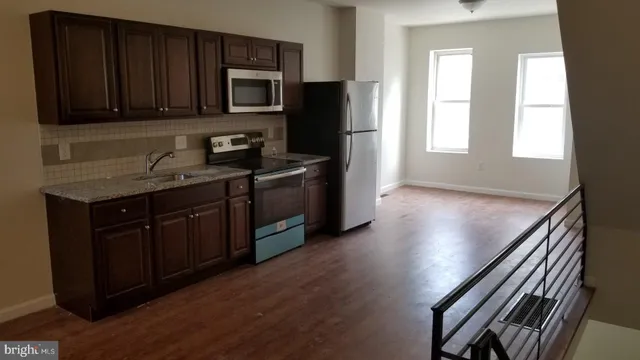 a kitchen with stainless steel appliances granite countertop a stove a sink and a microwave