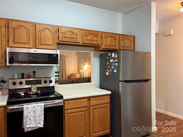 a kitchen with stainless steel appliances granite countertop a refrigerator a stove and a sink