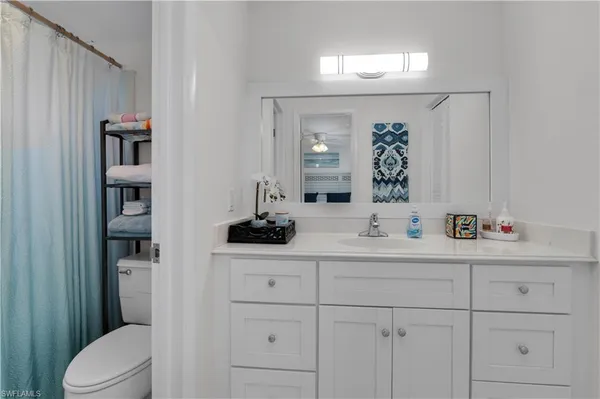 a bathroom with a granite countertop sink and a toilet