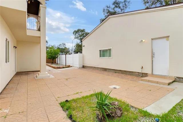a view of a patio with plants and large trees