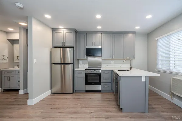 a kitchen with stainless steel appliances granite countertop a refrigerator a sink a stove and oven