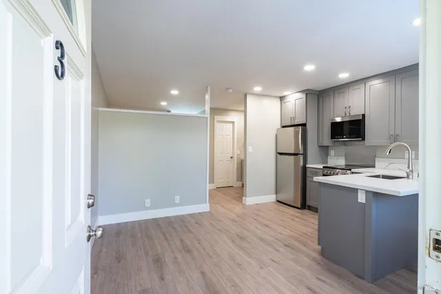 a view of a kitchen with a sink refrigerator and wooden floor