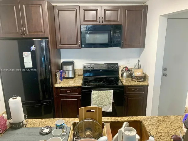 a kitchen with granite countertop cabinets stainless steel appliances and a sink
