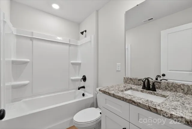 a bathroom with a granite countertop sink a toilet and bathtub