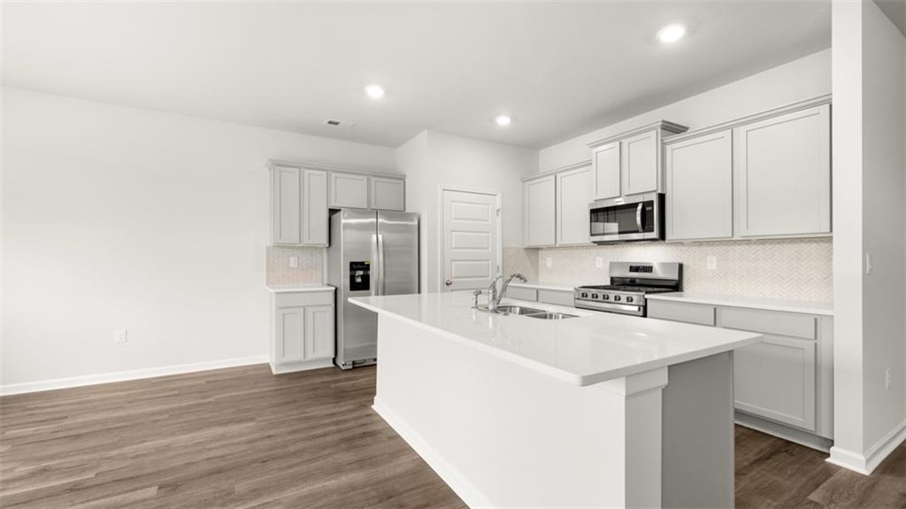 200 Defilippe Drive Statham, GA 30666 - Photo 9 of 60 a kitchen with kitchen island a white counter top space cabinets stainless steel appliances and wooden floor