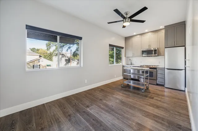 a kitchen with stainless steel appliances granite countertop a refrigerator a stove a microwave oven with a dining table and chairs with wooden floor