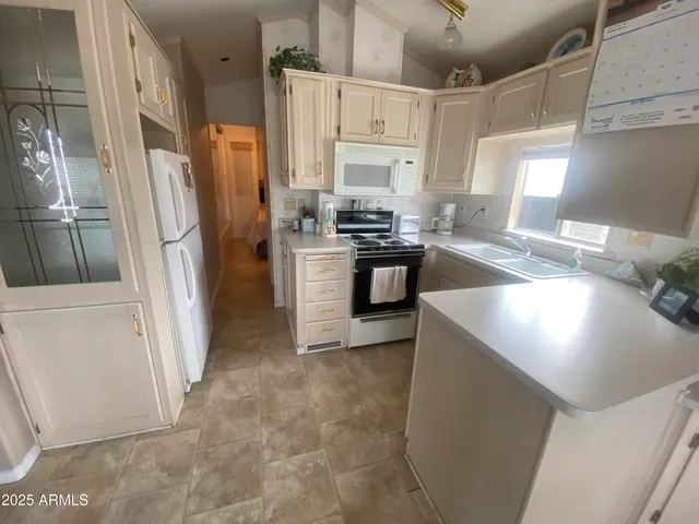 a kitchen with stainless steel appliances granite countertop a refrigerator a stove a sink and white countertops with wooden floor