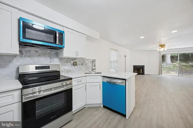 a kitchen with stainless steel appliances granite countertop a stove top oven a sink dishwasher and a microwave oven with wooden floor