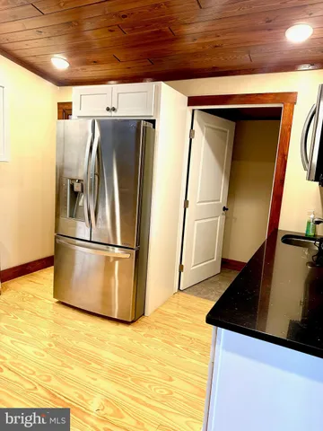 a view of a refrigerator in kitchen and an empty room
