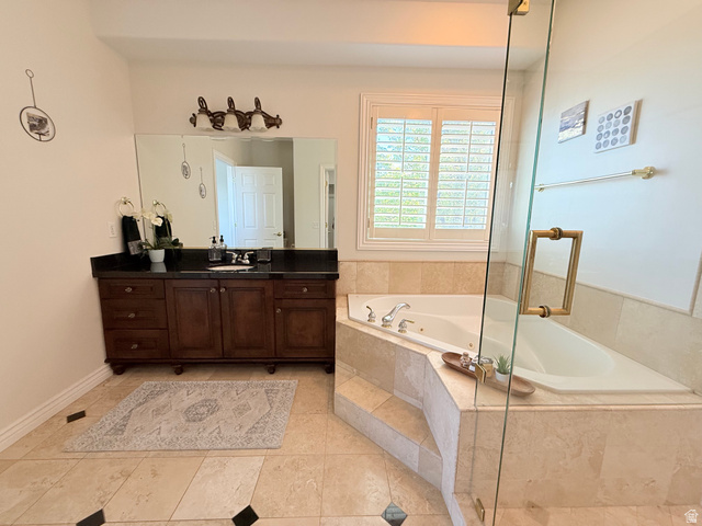 1562 Fairway Ridge Road Draper, UT 84020 - Photo 28 of 60 Built-in corner soaking tub with surround, dark wood vanity with a black countertop, large vanity mirror, plantation shutters, and glass shower enclosure with brass-tone hardware