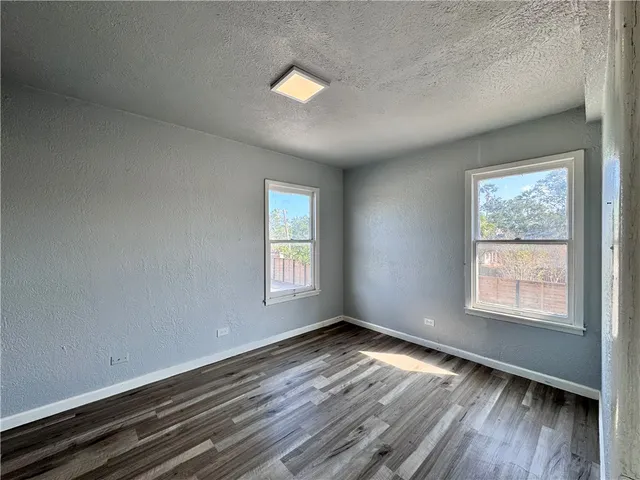 a view of an empty room with wooden floor and closet