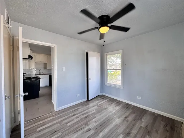 a view of empty room with wooden floor and fan